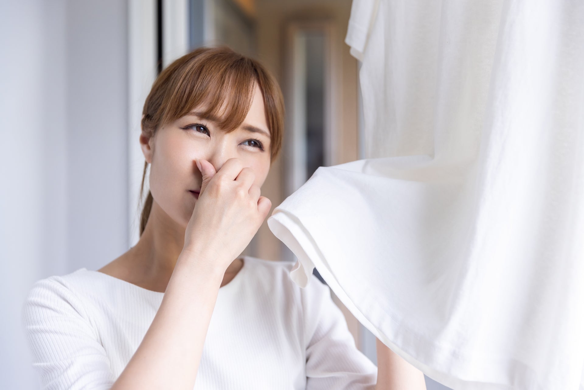 洗濯物の臭いに鼻をつまむ女性