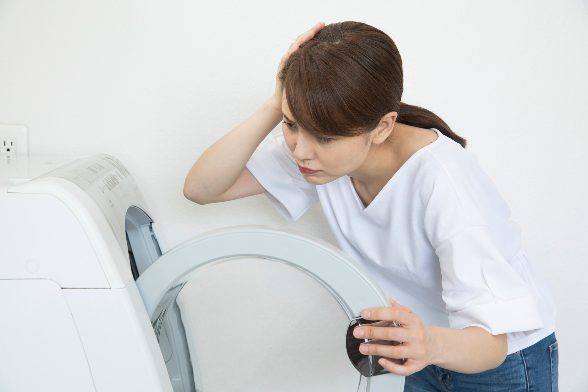 洗濯機が故障し頭を抱える女性