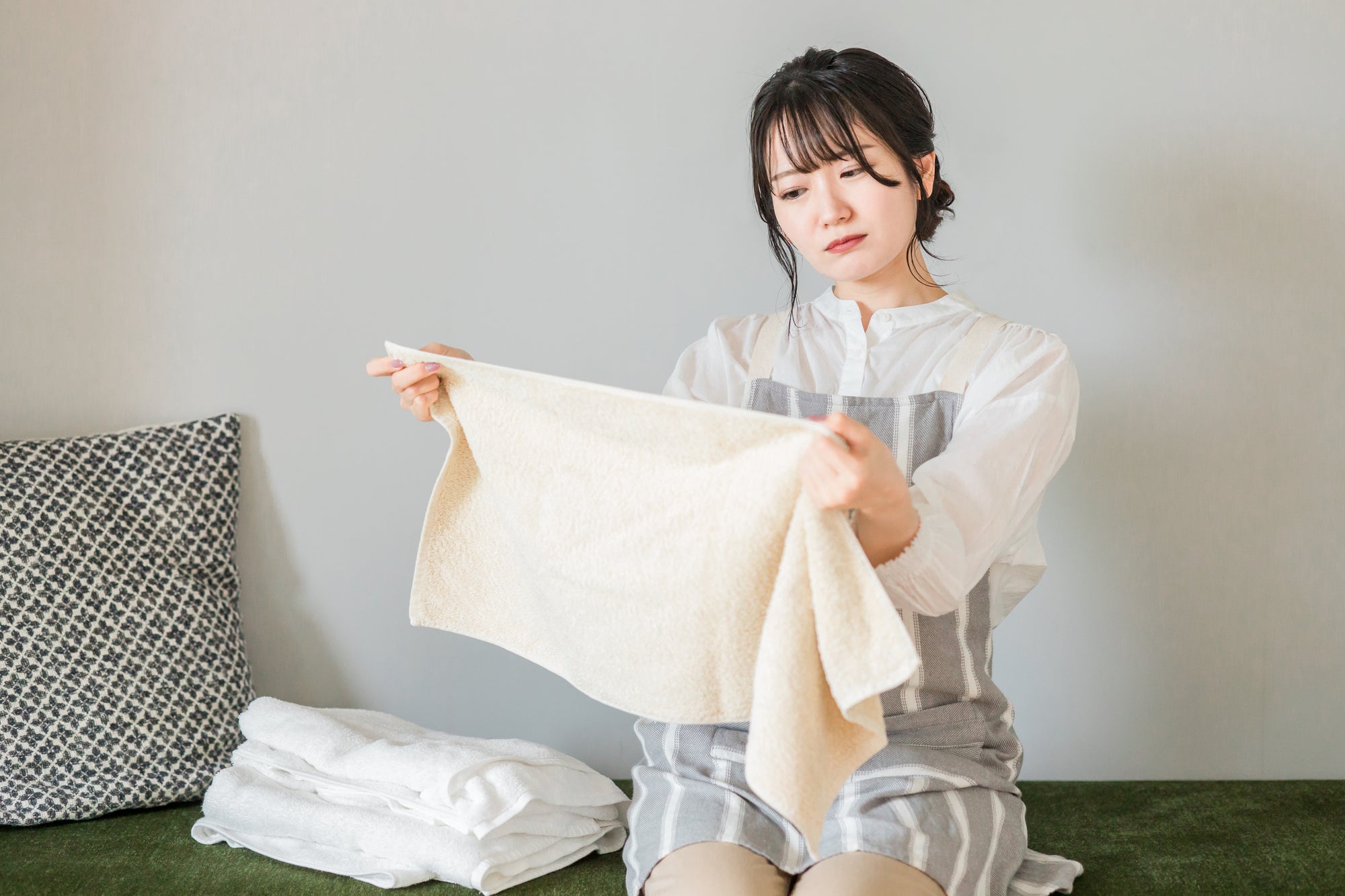 生乾きのタオルを見つめる女性