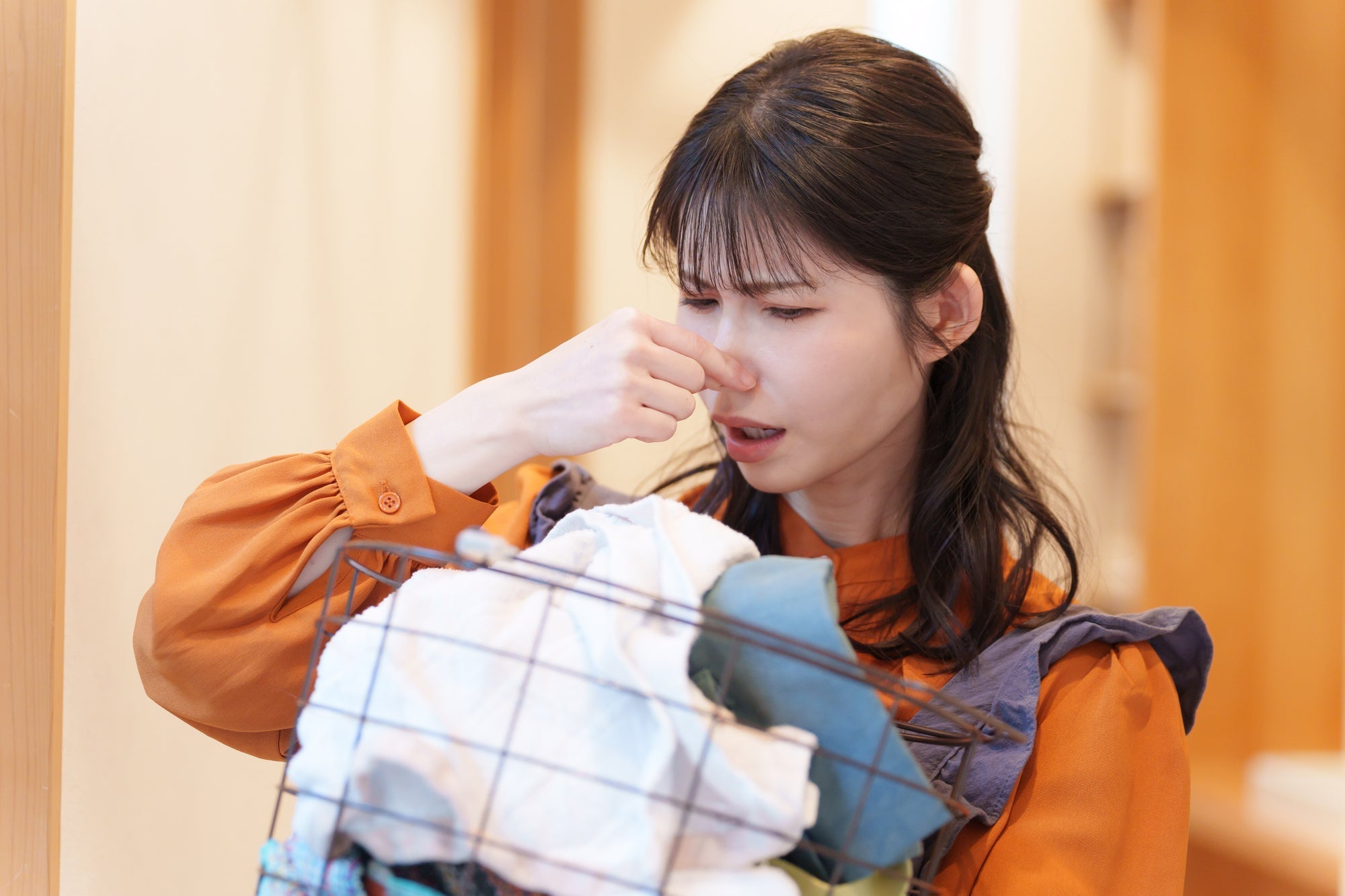 洗濯物を持ち鼻をつまむ女性