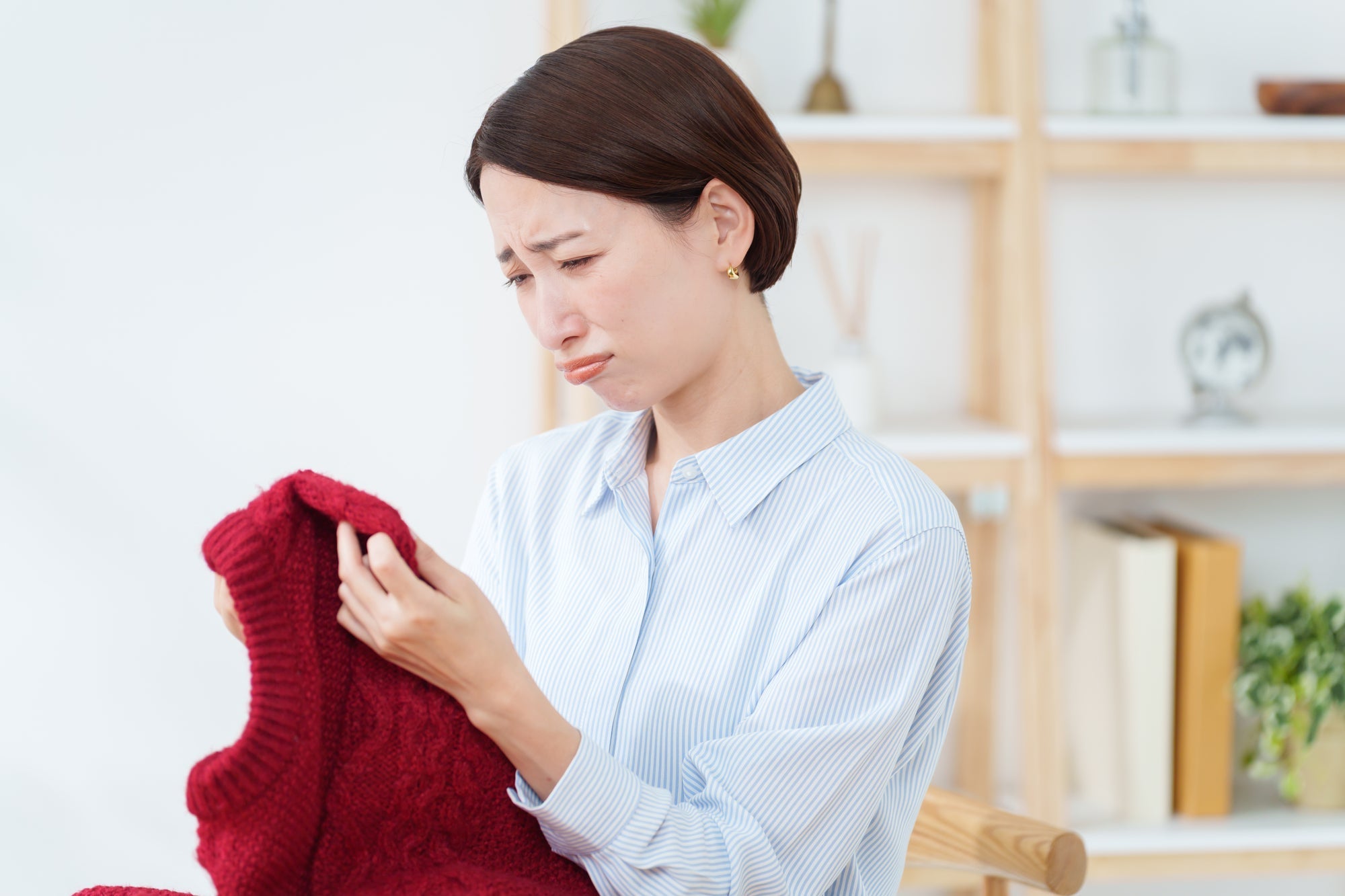 セーターを持ちながら悲しむ女性