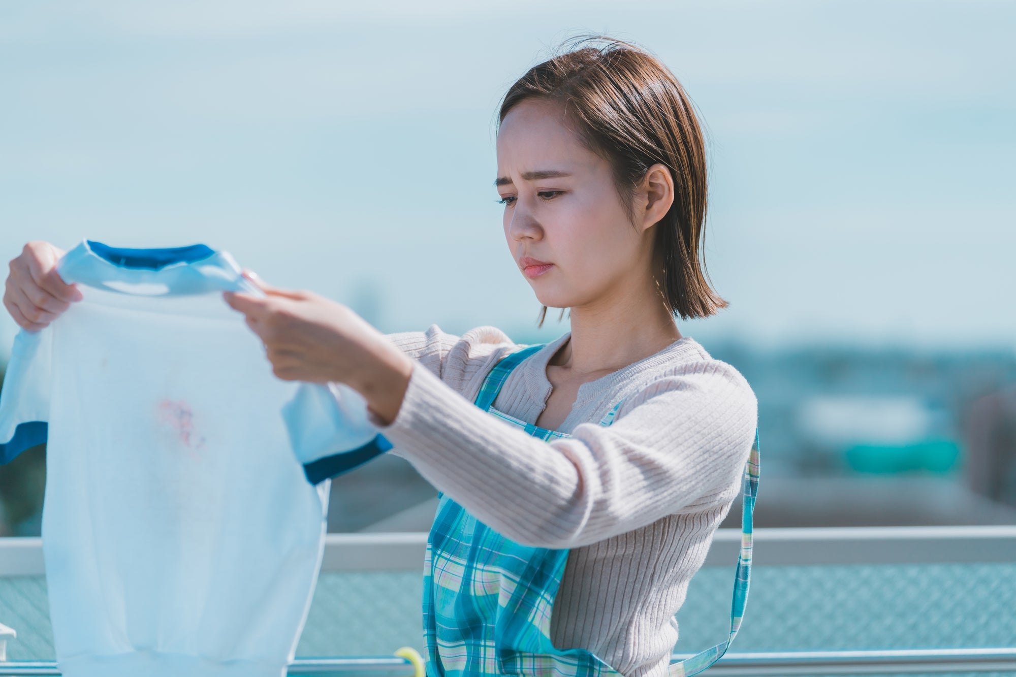 洗濯物を見ながら悩んでいる女性