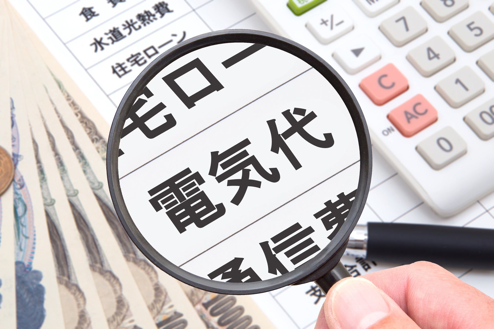虫眼鏡で電気代を覗く写真